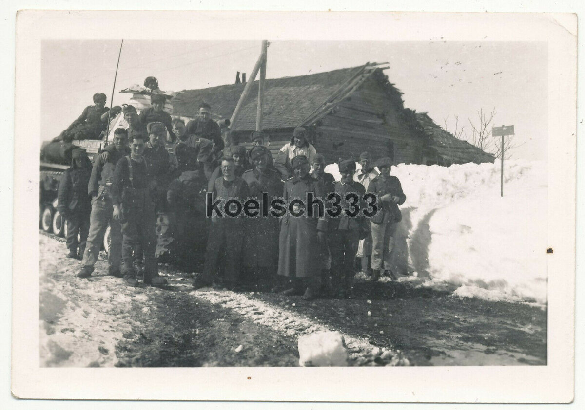 3 Landser vor einem Panzer der 7. Panzer Div. in Rshew Russland Winter 1942.jpg