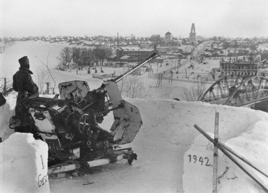 Немецкая 37-мм зенитная установка FlaK 37 у моста через Волгу в оккупированном Ржеве. На фоне города возвышается здание Оковецкой церкви. Немецкая 37-мм зенитная установка FlaK 37 у моста через Волгу в оккупированном Ржеве. На фоне города возвышается здание Оковецкой церкви.