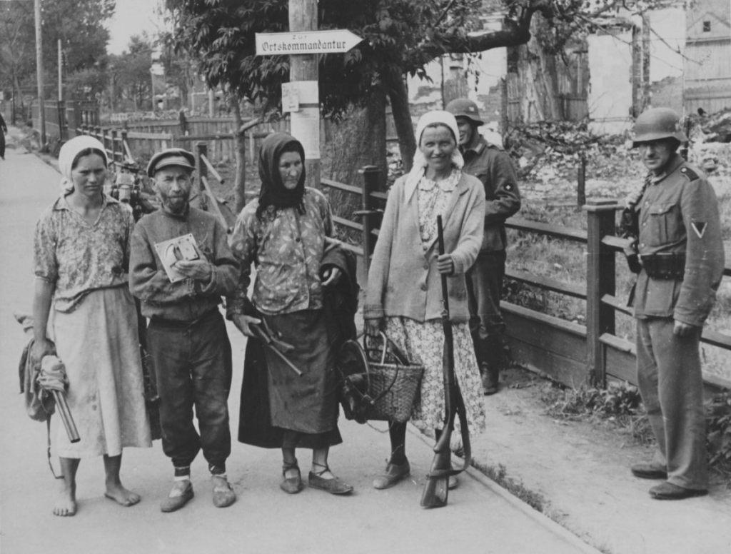 0 _ h Минск_1941г Жители несут охотружья(ИЖ-5 и др) и г-говорители в нем.комендатуру.jpg